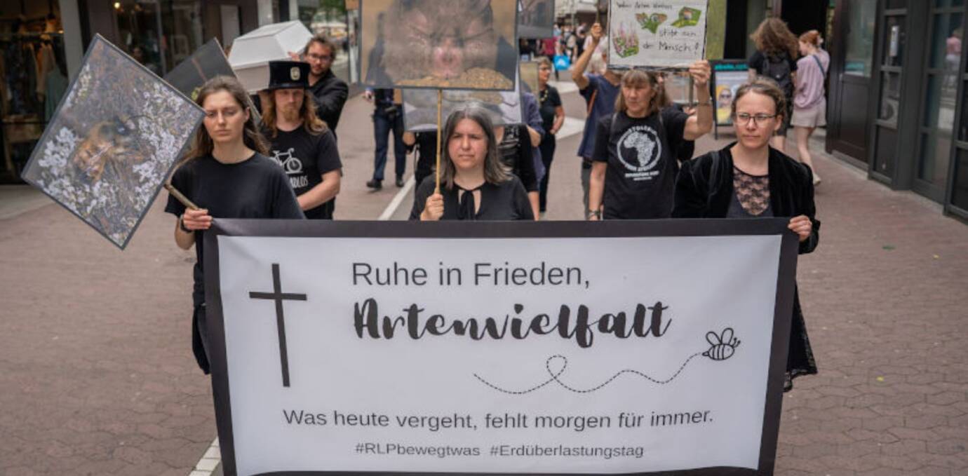 Menschen protestieren im Rahmen des Erdüberlastungstags in symbolischem Trauerzug für den Erhalt der Artenvielfalt