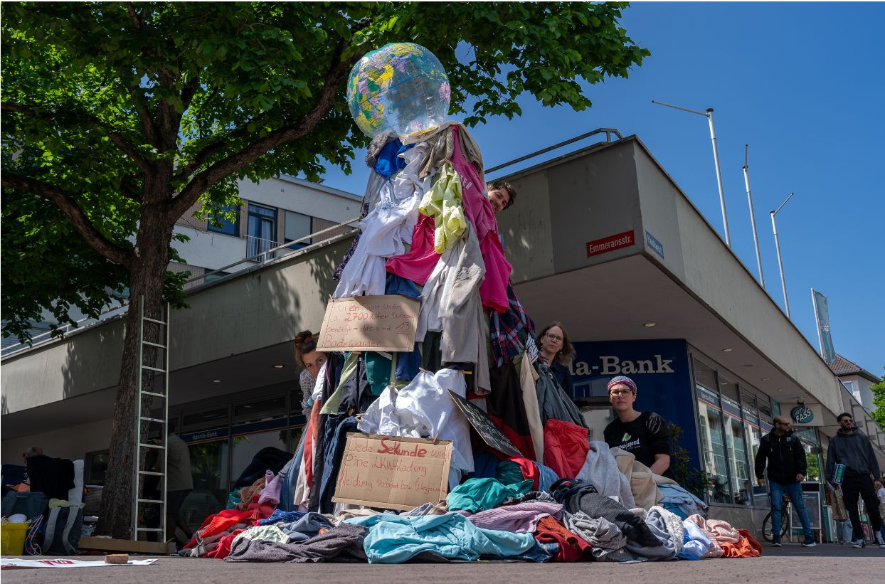 Kleiderberg mit Weltkugel bei Straßenprotest zu Fasft Fashion